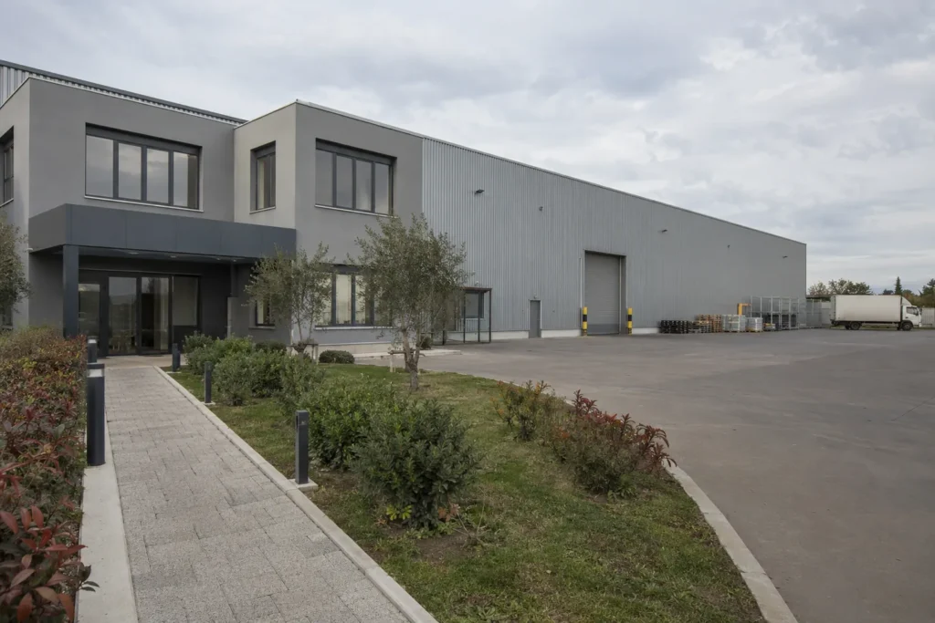 Fabrika yönetim binası önünde yeşil şerit, ayrı yaya yolu ve uzaktaki araç alanı