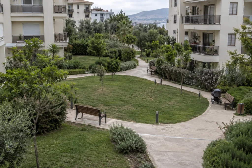 Apartman bahçesinde çim bölümlerini ayıran kıvrımlı yaya yolları ve banklar