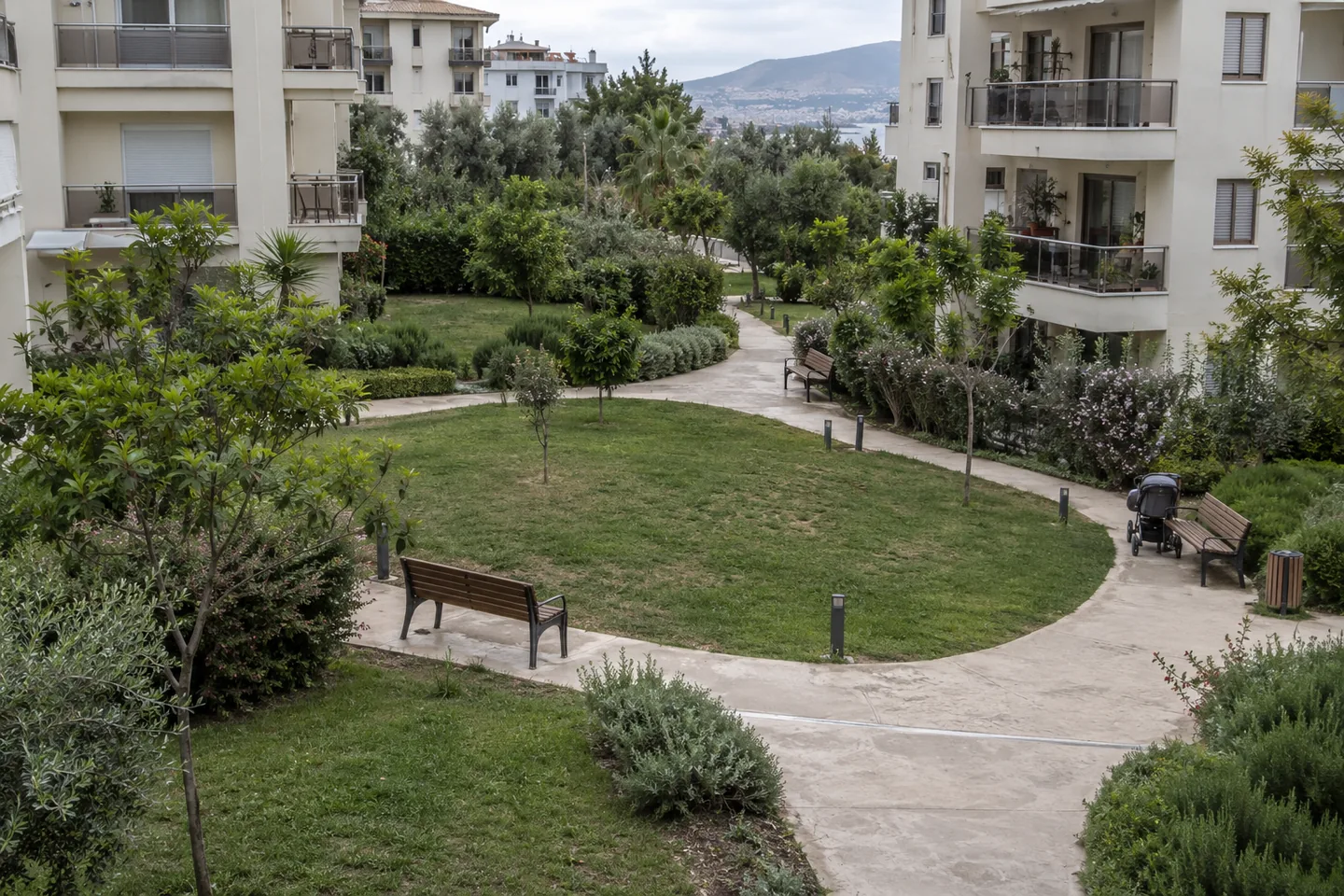 Apartman bahçesinde çim bölümlerini ayıran kıvrımlı yaya yolları ve banklar